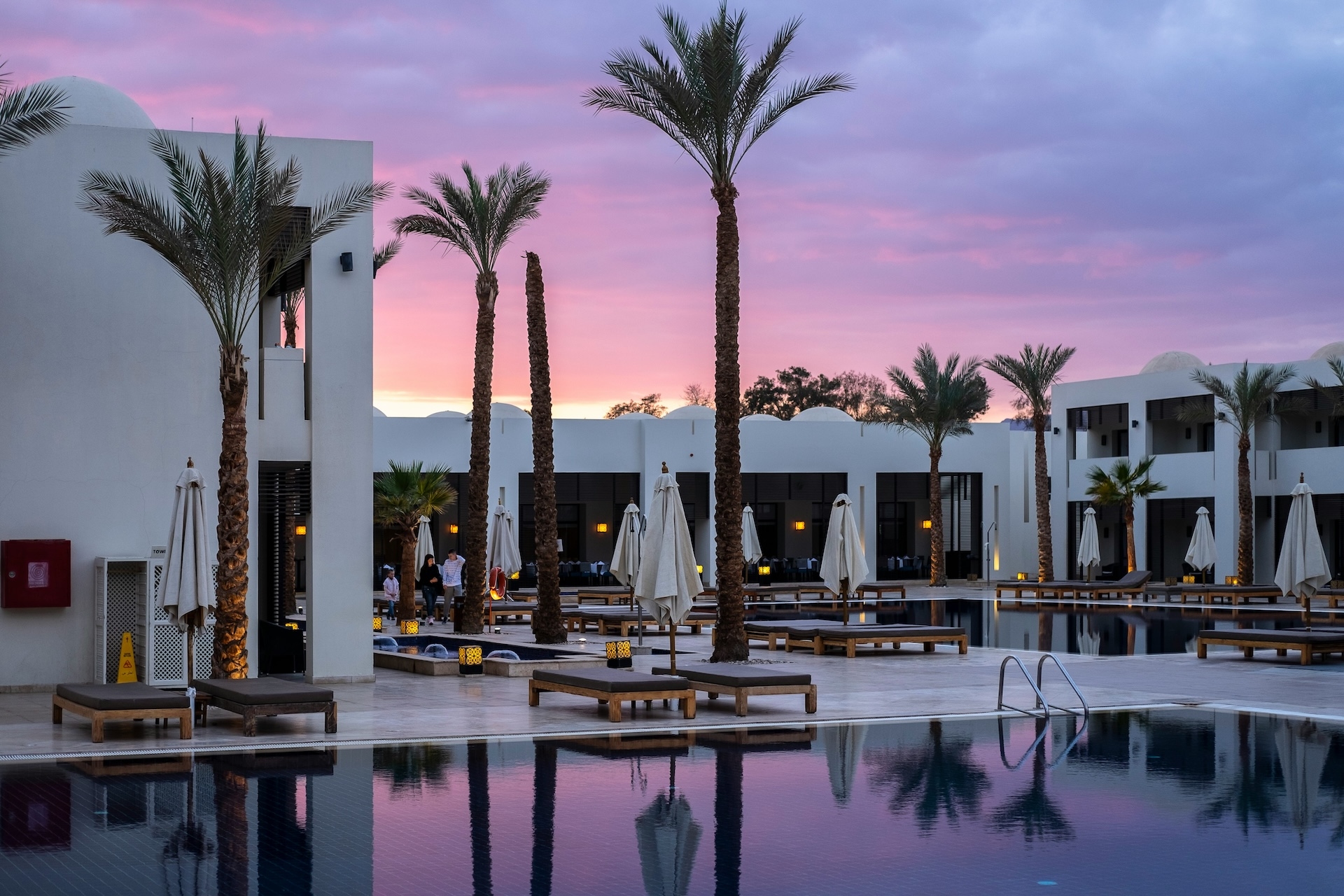 Luxury hotel pool at sunset with palm trees